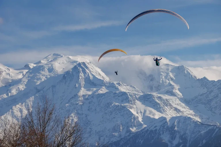 Parapente en vol au-dessus du Plateau d'Assy avec le massif du Mont-Blanc en arriere-plan